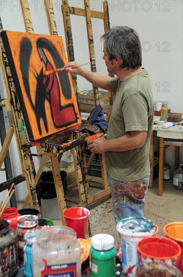 Mexico, Bajio, San Miguel de Allende, Artist Juan Ezcurdia in his studio working on painting set on easel. 
Photo : Nick Bonetti