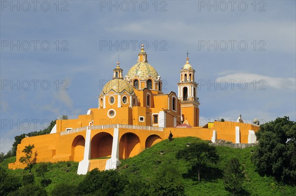Mexico, Puebla, Cholula, Church of Neustra Senor de los Remedios or Our Lady of Remedios on wooded hillside above the pyramid ruins with brightly painted exterior in neoclassical style. 
Photo : Nick Bonetti