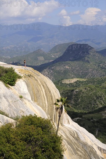 Mexico, Oaxaca, Hierve el Agua, Tourist standing on limestone cliff looking out over surrounding landscape. 
Photo : Nick Bonetti