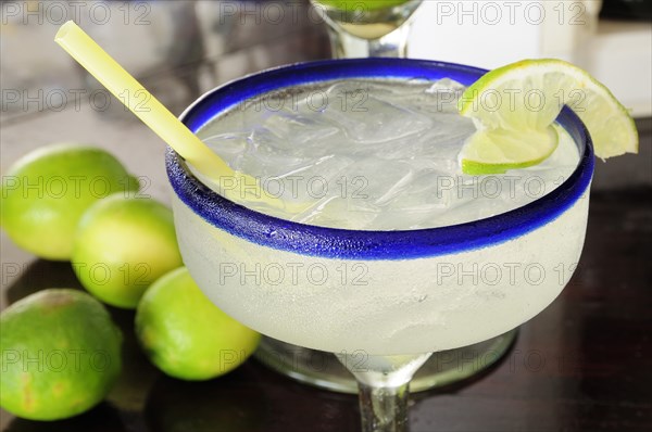 Mexico, Jalisco, Puerto Vallarta, Frosted glass of a margarita cocktail served with ice and slice of lime with whole limes at side. 
Photo : Nick Bonetti