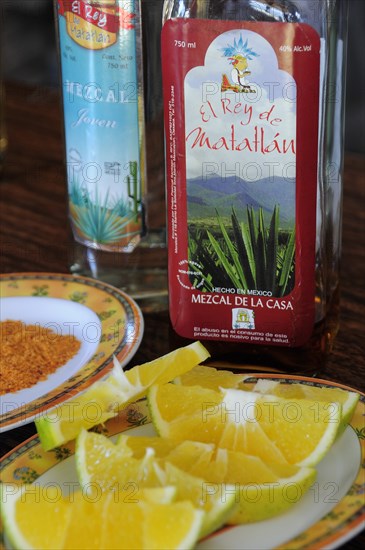 Mexico, Oaxaca, Bottles of Mezcal and plate of orange slices. 
Photo : Nick Bonetti