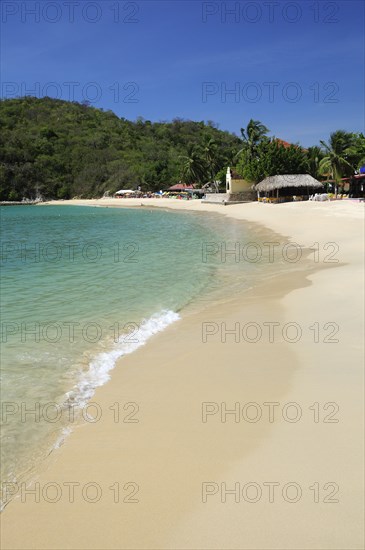 Mexico, Oaxaca, Huatulco, Bahia Santa Cruz View along stretch of sandy beach lined by restaurants and other buildings. 
Photo : Nick Bonetti