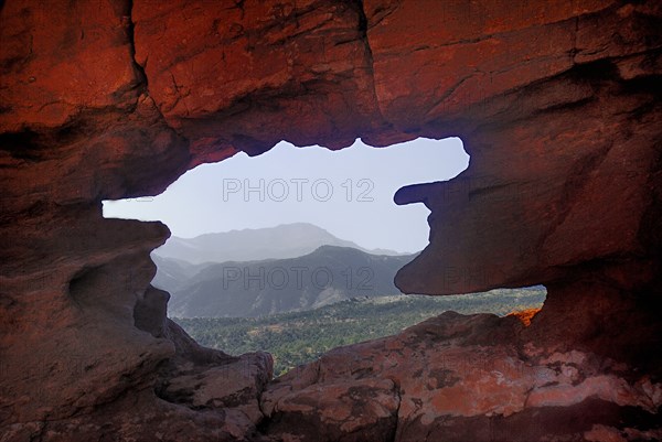 USA, Colorado, Colorado Springs, Garden of the Gods public park. Landscape view framed by irregular opening in rock formation. 
Photo : Hugh Rooney