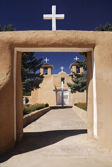 USA, New Mexico, Taos, Church of San Francisco de Asis. Entrance framing view to church exterior and white painted crosses. 
Photo : Hugh Rooney