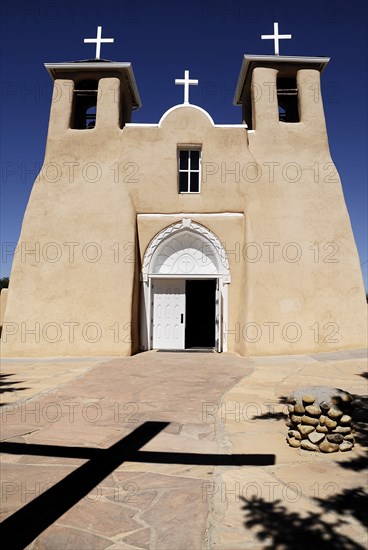 USA, New Mexico, Taos, Church of San Francisco de Asis. Exterior of church with deep shadow of cross cast across path to entrance in foreground. 
Photo : Hugh Rooney