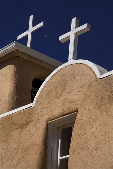 USA, New Mexico, Taos, Church of San Francisco de Asis. Detail of adobe style exterior architectecture and white painted crosses on rooftop. 
Photo : Hugh Rooney