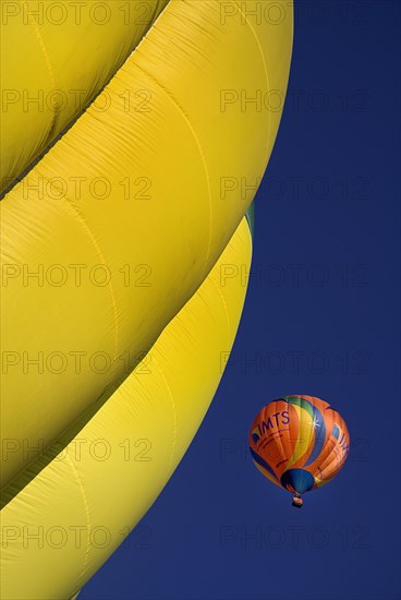 USA, New Mexico, Albuquerque, Annual balloon fiesta colourful hot air balloons ascending with part view of yellow ribbed edge in foreground. 
Photo : Hugh Rooney