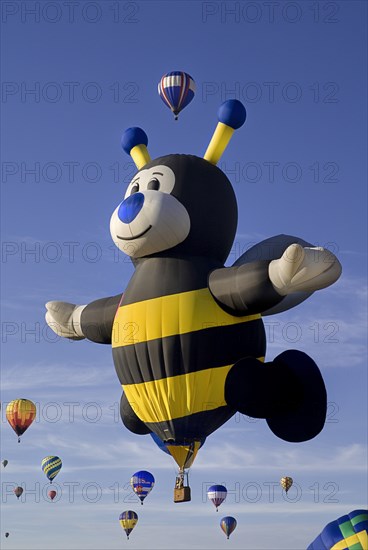 USA, New Mexico, Albuquerque, Annual balloon fiesta colourful hot air balloons ascending with bee-shaped balloon in foreground. 
Photo : Hugh Rooney