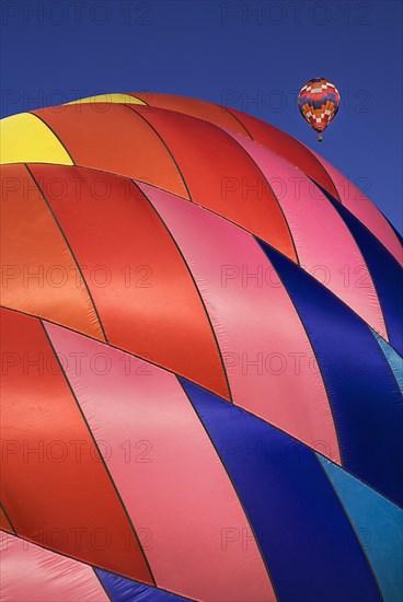USA, New Mexico, Albuquerque, Annual balloon fiesta colourful hot air balloons with part view of red pink and blue ribbed side of balloon in foreground. 
Photo : Hugh Rooney