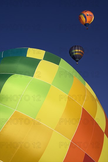 USA, New Mexico, Albuquerque, Annual balloon fiesta colourful hot air balloons with part view of green yellow and orange side of balloon being inflated in foreground. 
Photo : Hugh Rooney