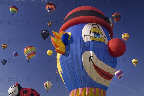USA, New Mexico, Albuquerque, Annual balloon fiesta colourful hot air balloons in flight. Balloon with the face of a clown in the foreground. 
Photo : Hugh Rooney