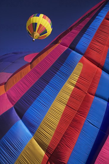 USA, New Mexico, Albuquerque, Annual balloon fiesta colourful hot air balloons in flight. Part view of striped balloon in the foreground. 
Photo : Hugh Rooney