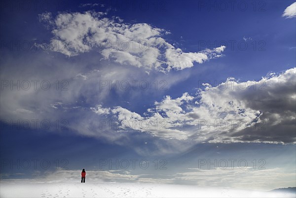 USA, New Mexico, Otero County, White Sands National Monunment. Landscape of white sand with dramatic cloudscape above. Single distant figure. 
Photo : Hugh Rooney