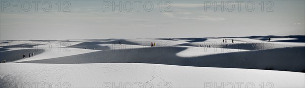 USA, New Mexico, Otero County, White Sands National Monunment. Landscape of white sand dunes with distant figures. 
Photo : Hugh Rooney