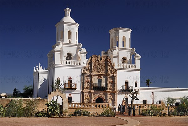 USA, Arizona, Tucson, Mission Church of San Xavier del Bac. Exterior facade with visitors at entrance. 
Photo : Hugh Rooney