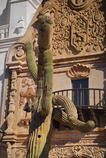 USA, Arizona, Tucson, Mission Church of San Xavier del Bac. Detail of balcony and carved window surround with cactus in foreground. 
Photo : Hugh Rooney