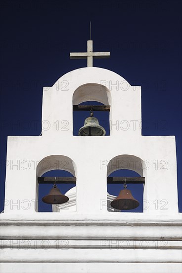 USA, Arizona, Tucson, Mission Church of San Xavier del Bac. White painted bell tower with three bells and topped with a cross. 
Photo : Hugh Rooney