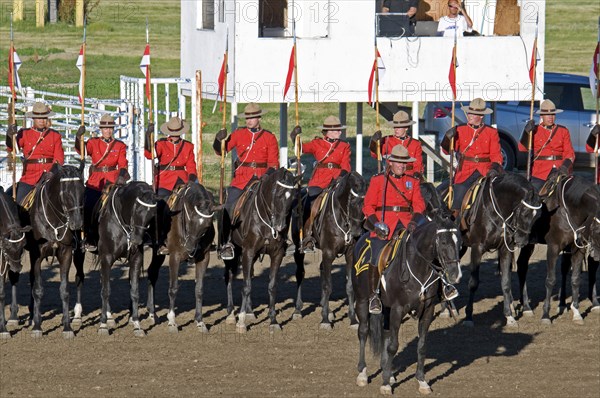 Canada, Alberta, Lethbridge, Royal Canadian Mounted Police Musical Ride RCMP cavalry in full dress red serge uniform on horseback holding lances with red and white pennons and commanding officer with sword drawn Mounties put on riding displays across Canada and around the world. 
Photo : Trevor Page