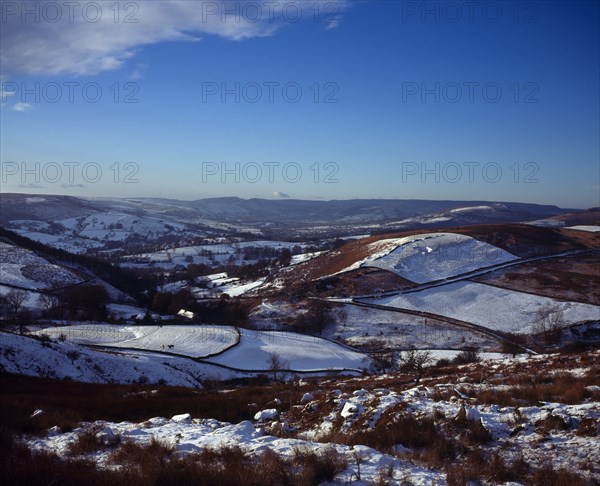 England, Derbyshire, Hathersage, View westwards over snow covered moorland landscape and fields towards Peak District village from Higgartor. 
Photo : Bryan Pickering