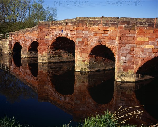 England, Hereford and Worcester, Eckington, Bridge on the B4080 crossing the River Avon and constructed from sandstone blocks reflected in the river below. 
Photo : Bryan Pickering