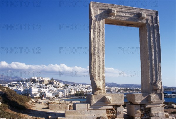 Greece, Aegean Islands, Cyclades, Naxos. Ruins of temple and the Portara Gateway marble doorway framing view of white painted Naxos Town below. 
Photo : Mike Southern