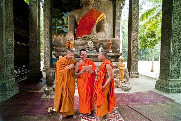 Cambodia, Siem Reap, Angkor Thom, Buddhist monks laughing at a picture on a digital reading tablet. 
Photo : Richard Rickard