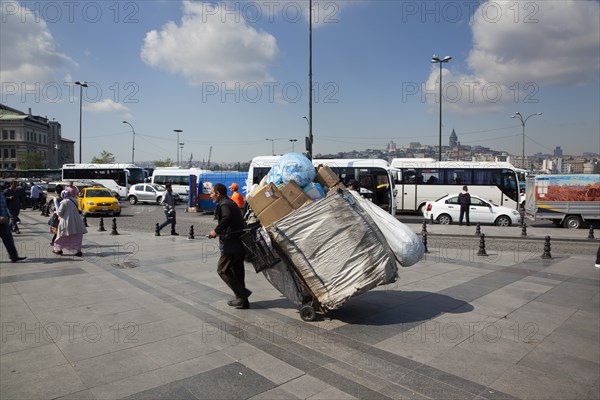 Turkey, Istanbul, Eminonu man transporting rubbish by handcart across the square outside the new mosque. 
Photo : Stephen Rafferty