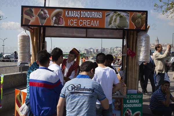 Turkey, Istanbul, Eminonu Ice cream vendor outside the New Mosque with young men waiting to be served. 
Photo : Stephen Rafferty
