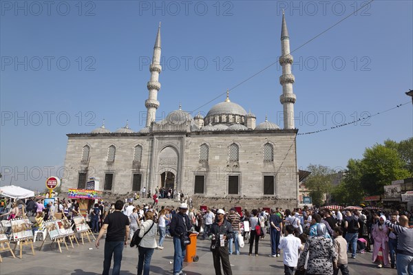 Turkey, Istanbul, Eminonu Yeni Camii New Mosque with people selling goods to the tourists in the square outside. 
Photo : Stephen Rafferty