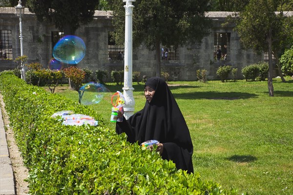 Turkey, Istanbul, Istanbul Sultanahmet woman selling bubble gun machine in park outside the Blue Mosque. 
Photo : Stephen Rafferty