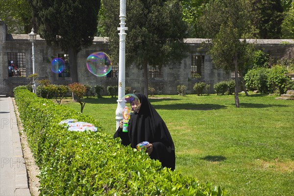 Turkey, Istanbul, Istanbul Sultanahmet woman selling bubble gun machine in park outside the Blue Mosque. 
Photo : Stephen Rafferty