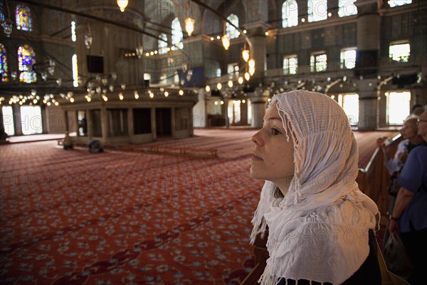 Turkey, Istanbul, Sultanahmet Camii Blue Mosque interior. Female visitor wearing headscarf looking upwards. 
Photo : Stephen Rafferty