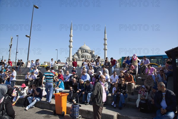 Turkey, Istanbul, Eminonu Yeni Camii New Mosque people on sat on steps next to the subway. 
Photo : Stephen Rafferty