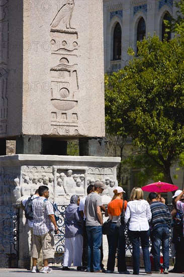 Turkey, Istanbul, Sultanahmet Tourists in the Roman Hippodrome in At Meydani beside Egyptian Obelisk with Hieroglyphics from Luxor and relief at base showing Theodosius I and courtiers. 
Photo : Paul Seheult