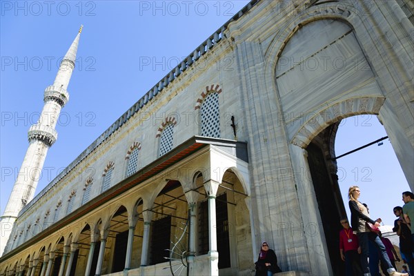 Turkey, Istanbul, Sultanahmet Camii The Blue Mosque exterior wall of the Courtyard with minaret and visiting sightseeing tourist. 
Photo : Paul Seheult