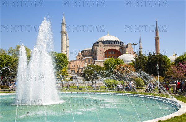 Turkey, Istanbul, Sultanahmet Haghia Sophia with dome and minarets beyond the water fountain in the gardens with sightseeing tourists. 
Photo : Paul Seheult