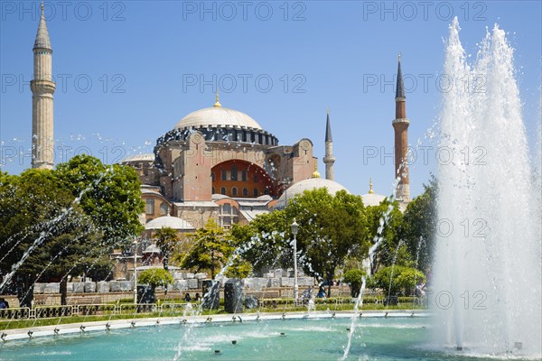 Turkey, Istanbul, Sultanahmet Haghia Sophia with dome and minarets beyond the water fountain in the gardens with sightseeing tourists. 
Photo : Paul Seheult