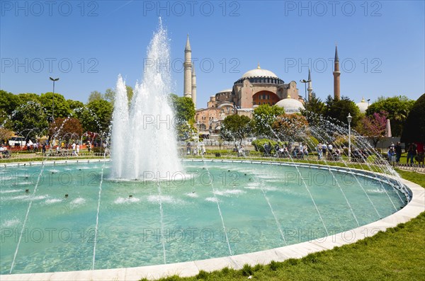 Turkey, Istanbul, Sultanahmet Haghia Sophia with dome and minarets beyond the water fountain in the gardens with sightseeing tourists. 
Photo : Paul Seheult