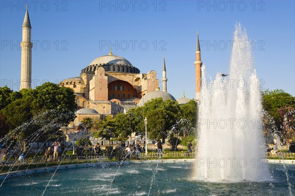 Turkey, Istanbul, Sultanahmet Haghia Sophia with dome and minarets beyond the water fountain in the gardens with sightseeing tourists. 
Photo : Paul Seheult