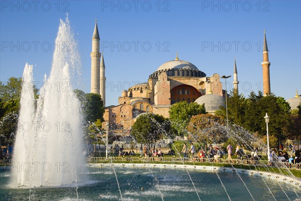 Turkey, Istanbul, Sultanahmet Haghia Sophia with dome and minarets beyond the water fountain in the gardens with sightseeing tourists. 
Photo : Paul Seheult