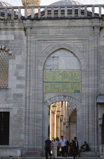 Turkey, Istanbul, Sultanahmet Camii The Blue Mosque with people passing through the entrance to the Courtyard beneath Arabic text from the Koran. 
Photo : Paul Seheult