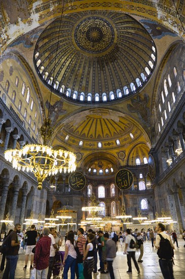 Turkey, Istanbul, Sultanahmet Haghia Sophia Sightseeing tourists beneath the dome with murals and chandeliers in the Nave of the Cathedral. 
Photo : Paul Seheult