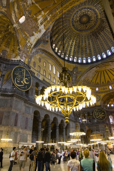 Turkey, Istanbul, Sultanahmet Haghia Sophia Sightseeing tourists beneath the dome with murals and chandeliers in the Nave of the Cathedral. 
Photo : Paul Seheult