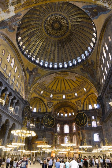 Turkey, Istanbul, Sultanahmet Haghia Sophia Sightseeing tourists beneath the dome with murals and chandeliers in the Nave of the Cathedral. 
Photo : Paul Seheult