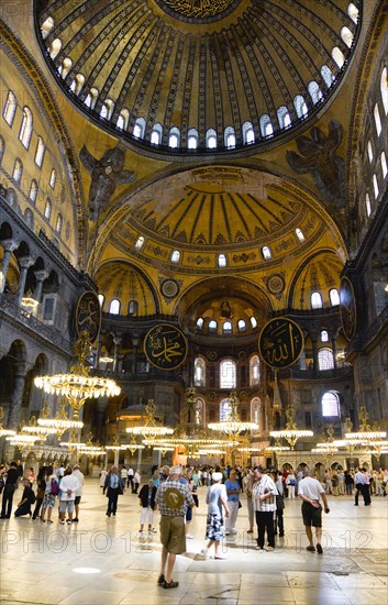 Turkey, Istanbul, Sultanahmet Haghia Sophia Sightseeing tourists beneath the dome with murals and chandeliers in the Nave of the Cathedral. 
Photo : Paul Seheult