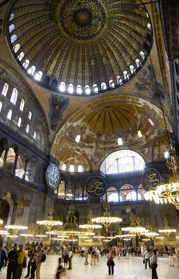 Turkey, Istanbul, Sultanahmet Haghia Sophia Sightseeing tourists beneath the dome with murals and chandeliers in the Nave of the Cathedral. 
Photo : Paul Seheult