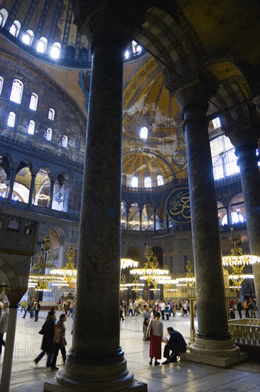 Turkey, Istanbul, Sultanahmet Haghia Sophia Sightseeing tourists beneath the dome with murals and chandeliers in the Nave of the Cathedral. 
Photo : Paul Seheult