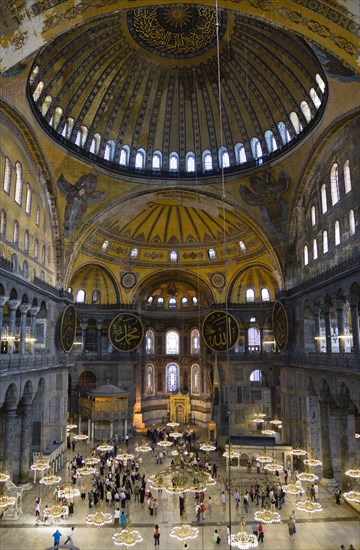 Turkey, Istanbul, Sultanahmet Haghia Sophia Sightseeing tourists beneath the dome with murals and chandeliers in the Nave of the Cathedral. 
Photo : Paul Seheult