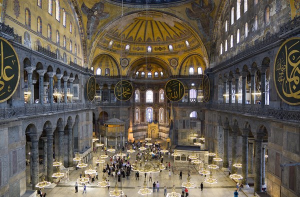 Turkey, Istanbul, Sultanahmet Haghia Sophia Sighseeing tourists beneath the dome with murals and chandeliers in the Nave of the Cathedral. 
Photo : Paul Seheult