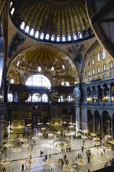 Turkey, Istanbul, Sultanahmet Haghia Sophia Sightseeing tourists beneath the dome with murals and chandeliers in the Nave of the Cathedral. 
Photo : Paul Seheult